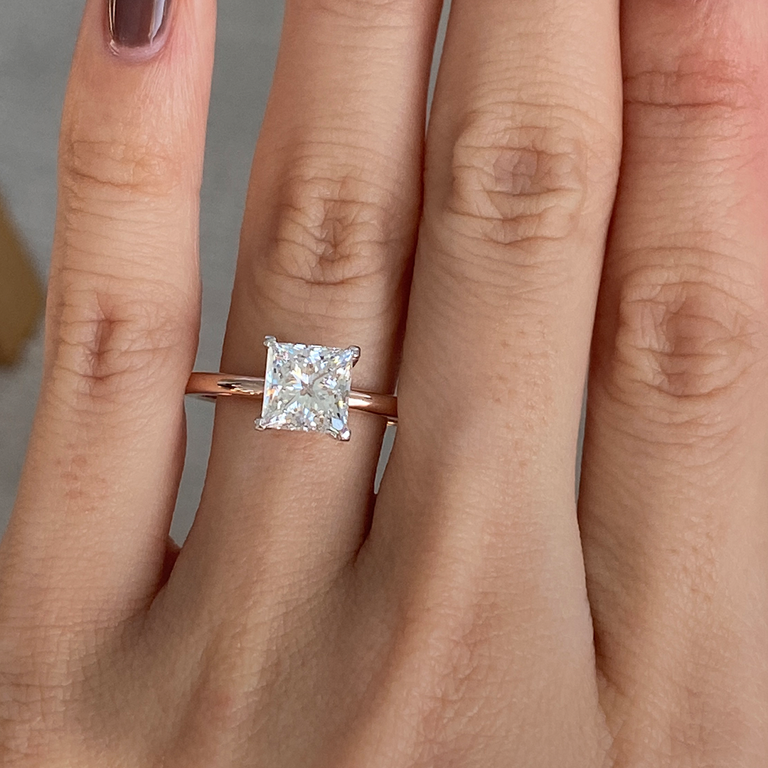 Hand with princess solitaire two tone ring.
