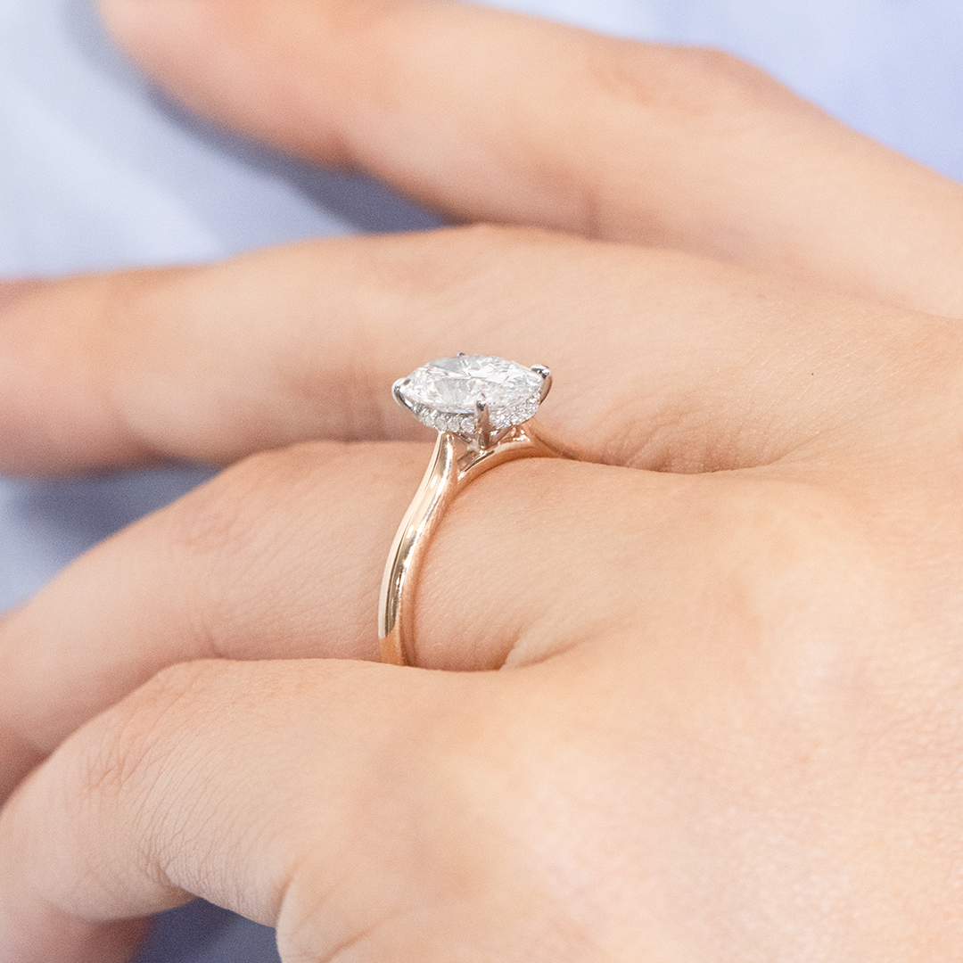 Hand with oval halo two tone ring.