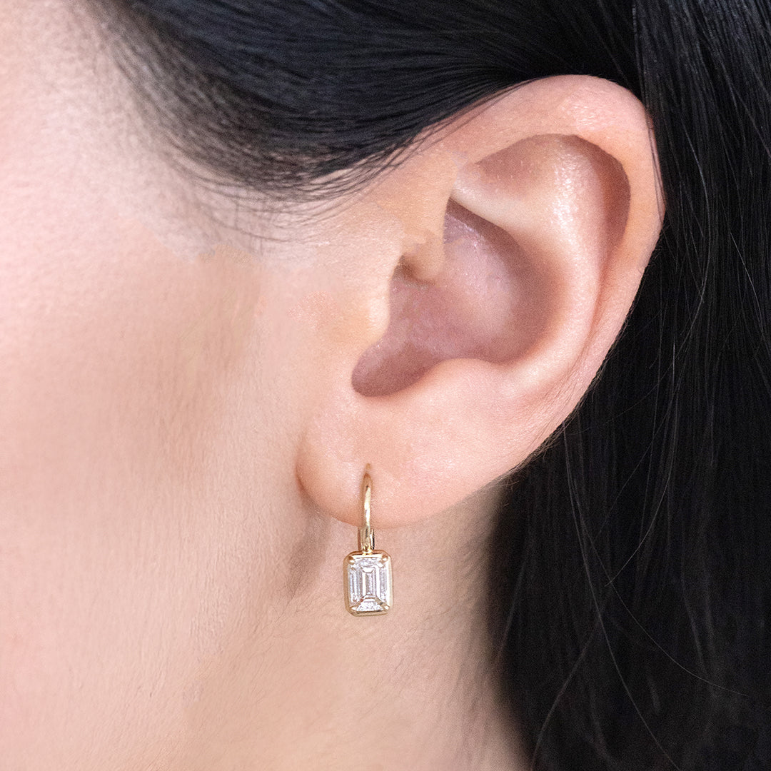 Diamond Drop Earrings on Ear, Emerald Cut, Yellow Gold.