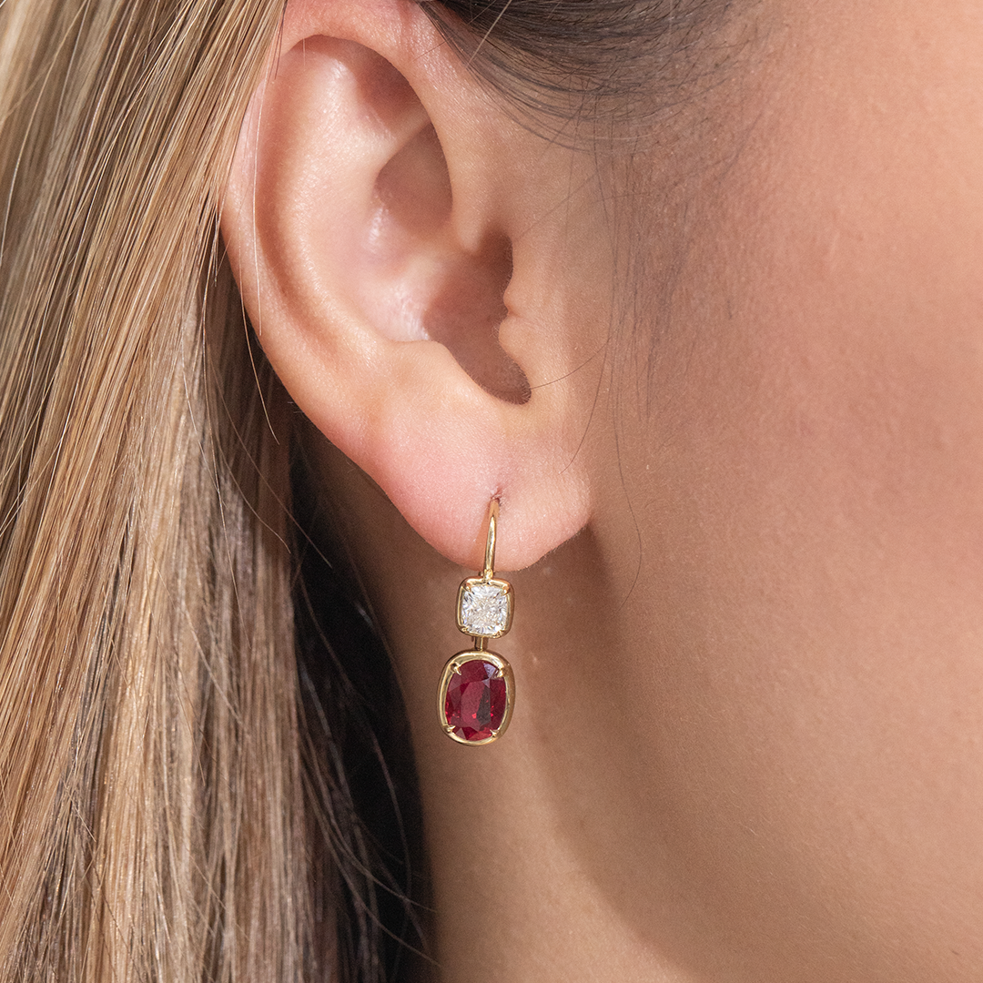 Earrings worn on ear, oval red rubies, cushion diamonds.