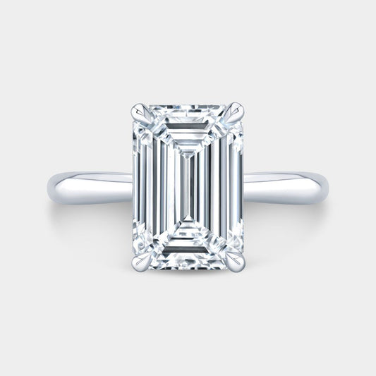 Emerald-cut diamond solitaire engagement ring with hidden halo and tapered cathedral in platinum