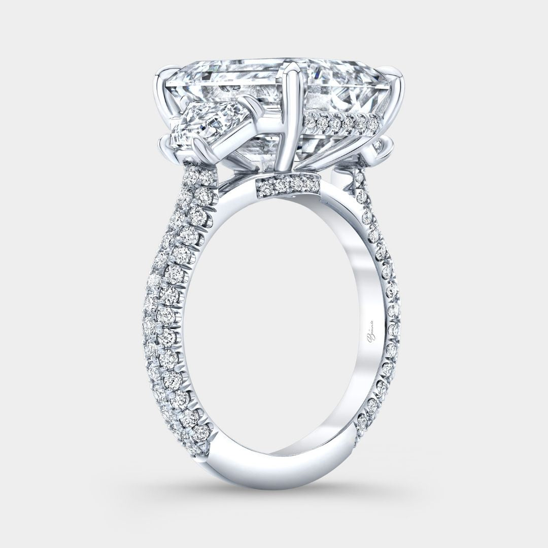 Platinum emerald diamond ring with hidden halo and triple pavé band design