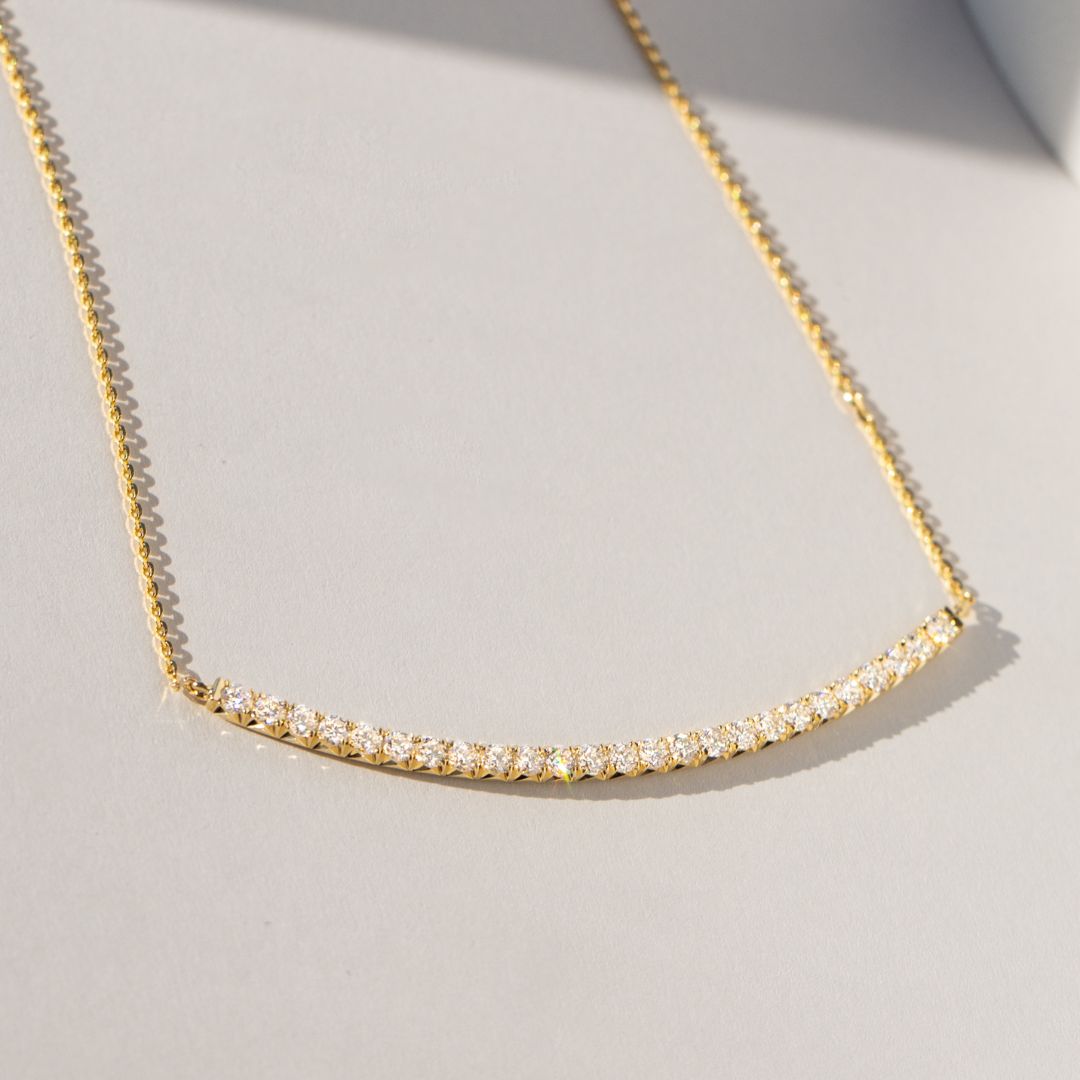 Necklace worn on person, lab grown diamonds, French pave curved bar pendant.