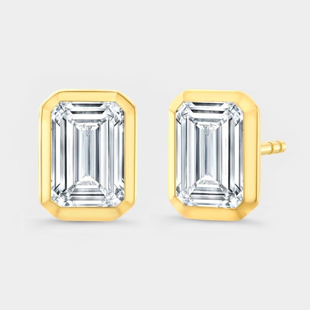 Gold emerald-cut stud earrings on a light gray background