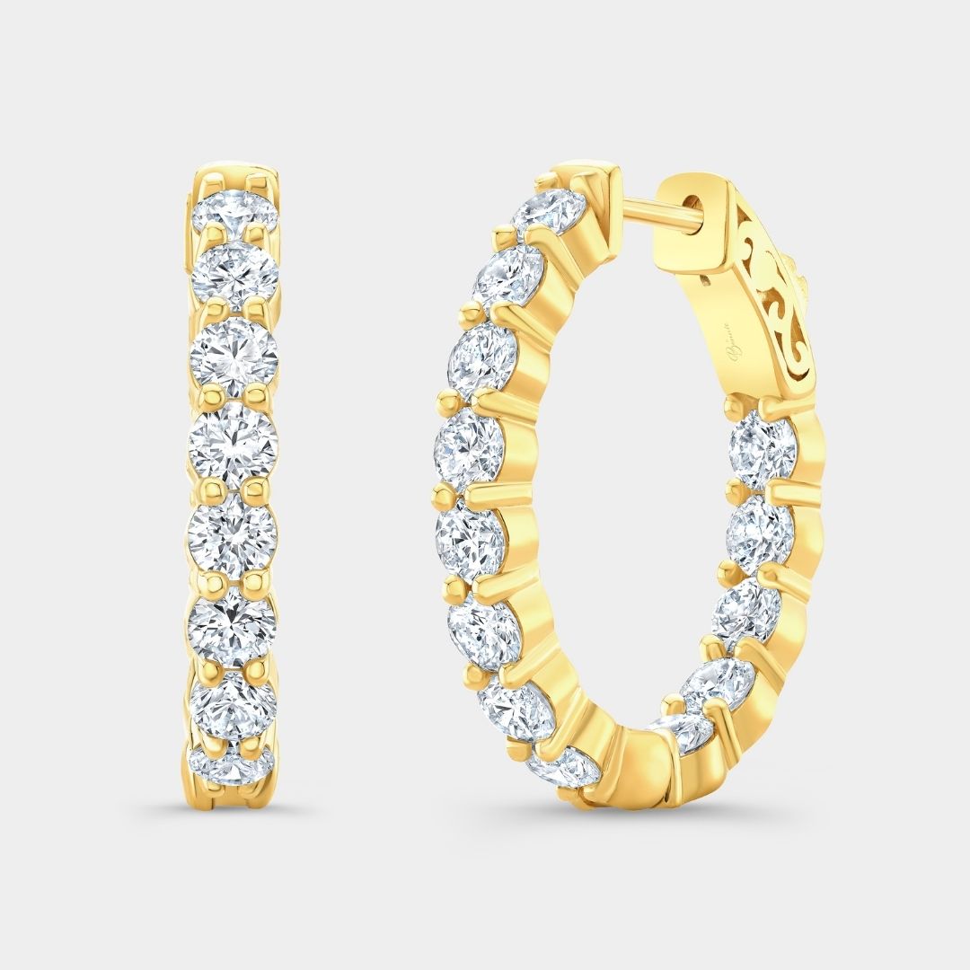 Gold hoop earrings with clear gemstones on a light gray background