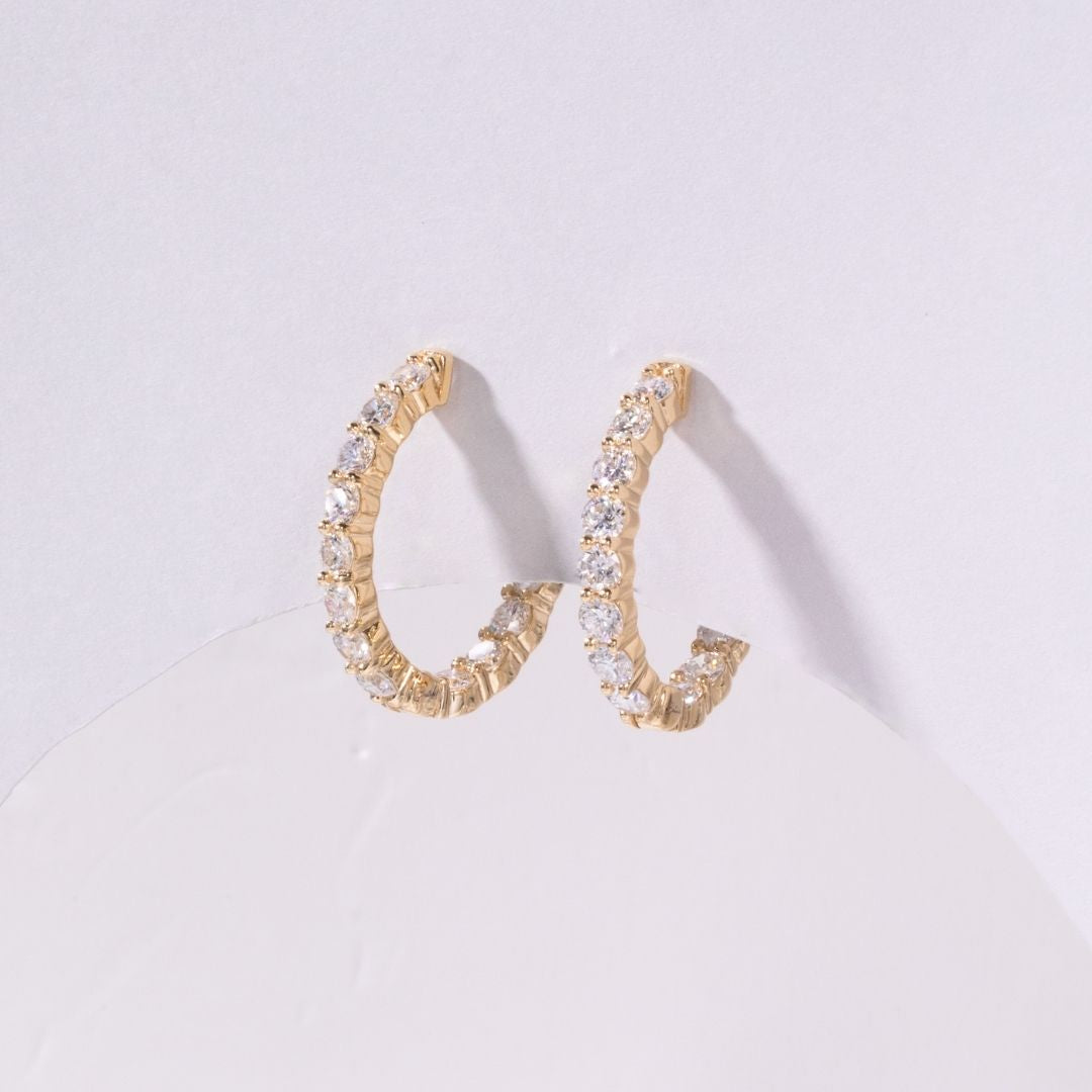 Gold hoop earrings with clear stones on a light gray background