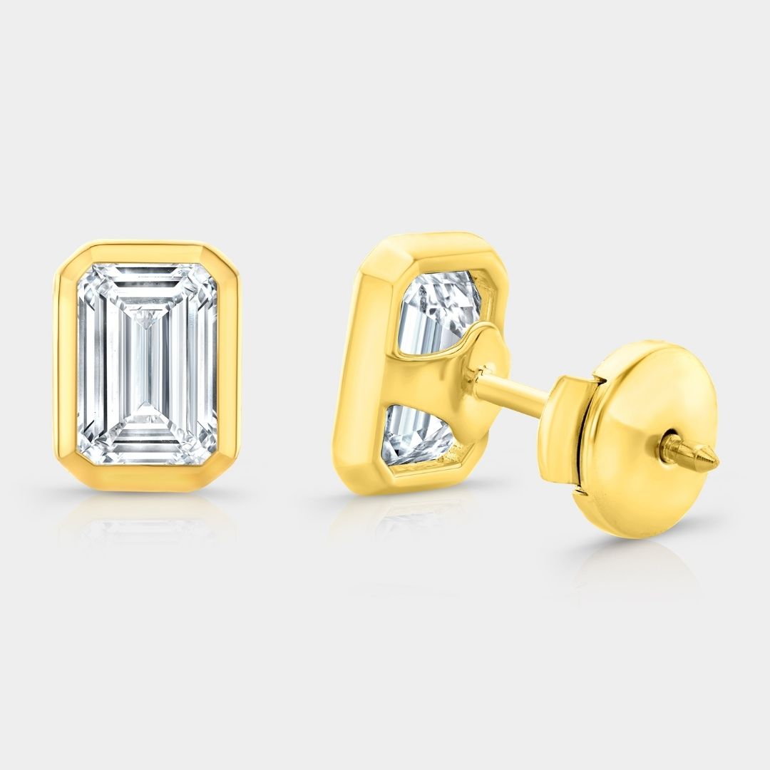 Gold earrings with emerald-cut gemstones on a white background