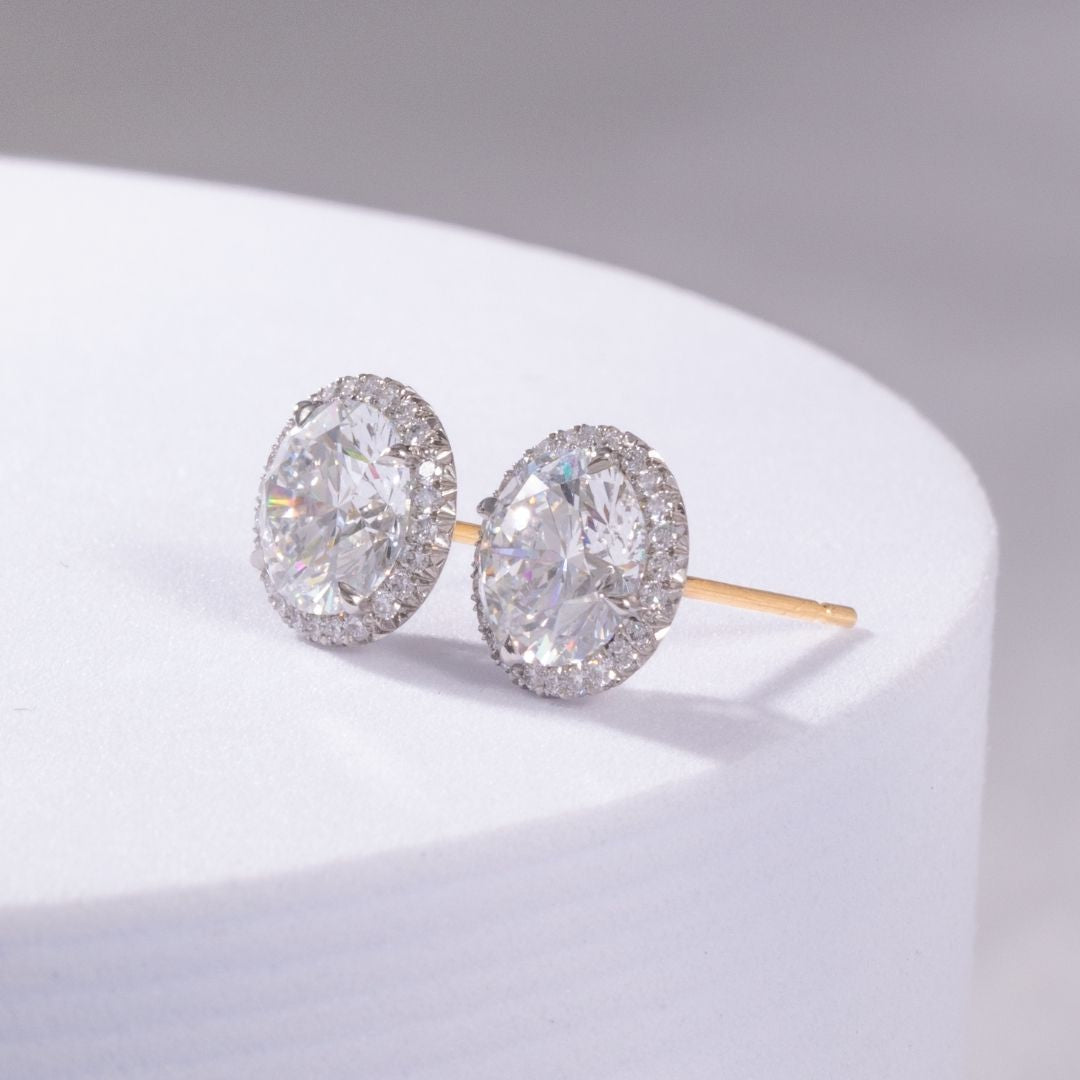 Pair of diamond earrings on a white platform with a gray background