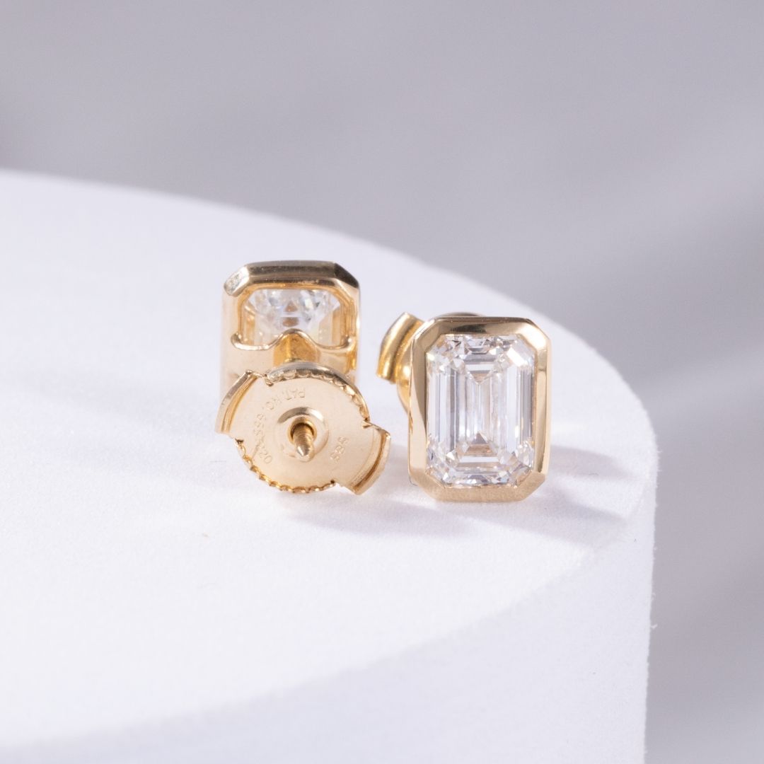 Gold earrings with clear gemstones on a light gray background