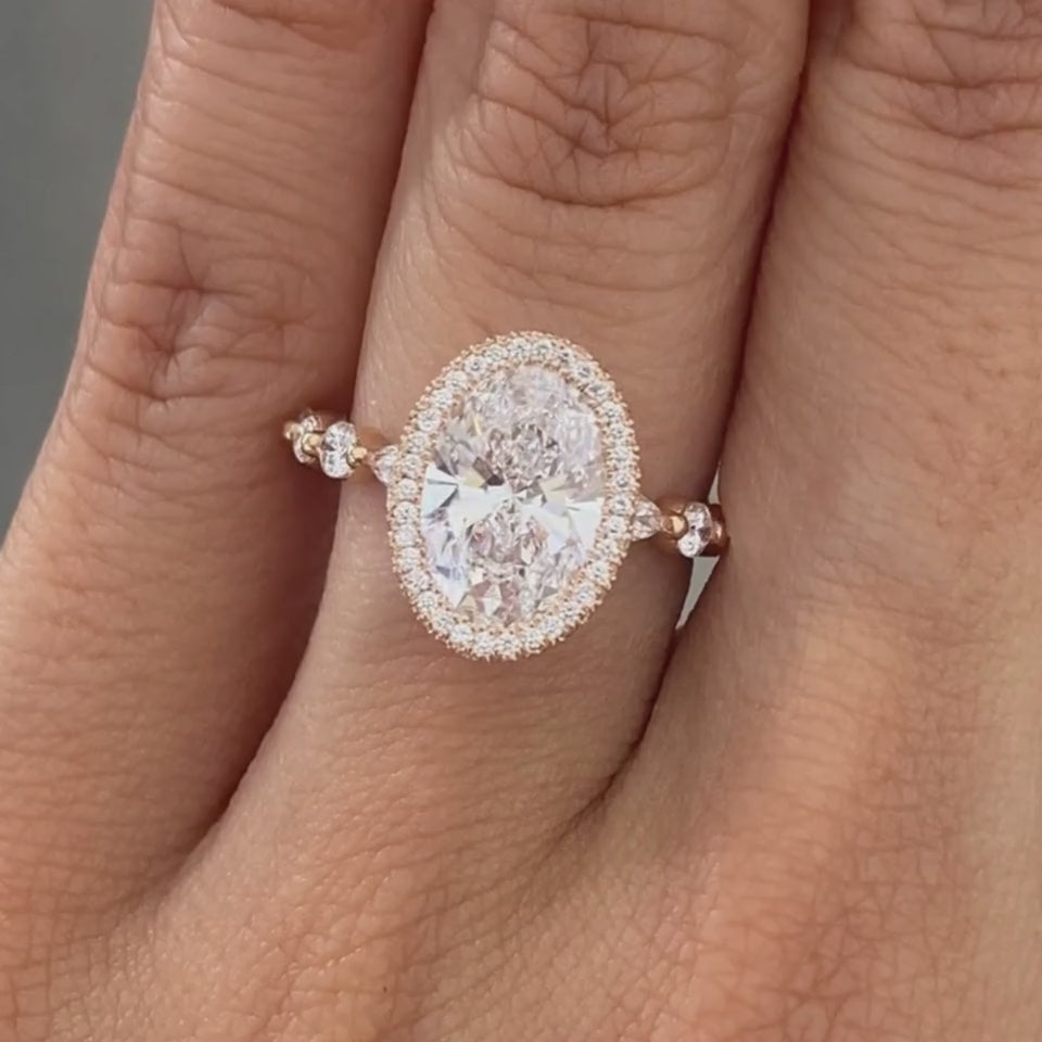 Video of oval diamond rose gold ring with seamless halo and marquise-round diamond details